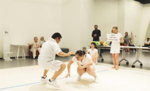 Teatr 21 lavastuses „Tisha B’av“ osalesid kaks treeneri või õpetaja rollis näitlejannat ning kaheksa Downi sündroomiga noort.